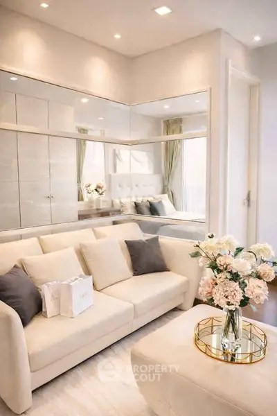 Elegant living room with beige sofa, mirrored wall, and floral centerpiece, exuding modern sophistication.
