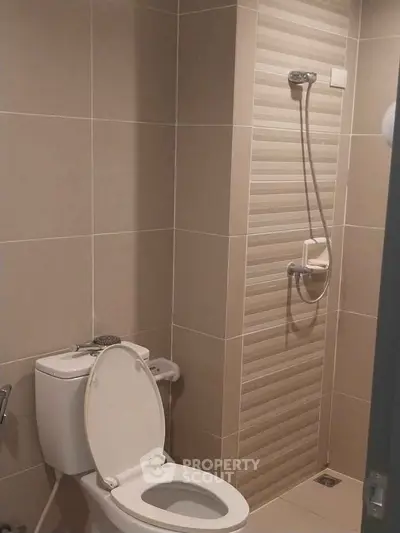 Modern bathroom with shower and toilet in a tiled setting.