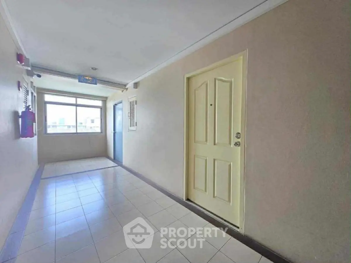 Spacious apartment corridor with natural light and secure entryway.