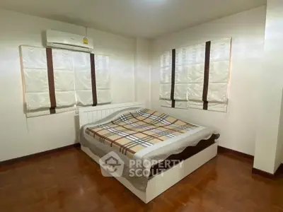 Cozy bedroom with parquet flooring and air conditioning, featuring a stylish bed and elegant window treatments.