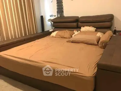 Spacious bedroom with large brown leather bed and cozy pillows