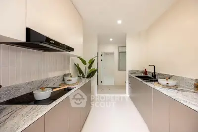 Modern kitchen with sleek countertops and dual sink setup, featuring a minimalist design and ample lighting.