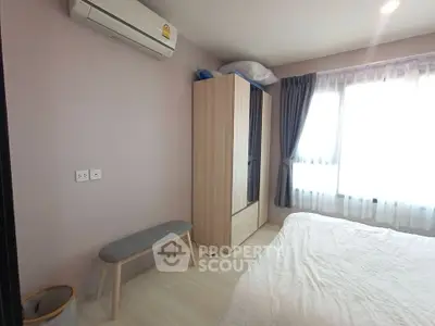 Cozy bedroom with natural light, featuring a wardrobe, air conditioning, and a comfortable bed.