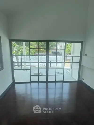 Spacious room with large glass doors leading to a balcony, offering a serene outdoor view.