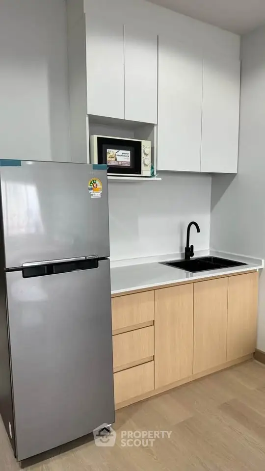 Modern kitchen with sleek cabinetry and stainless steel fridge in a compact layout.