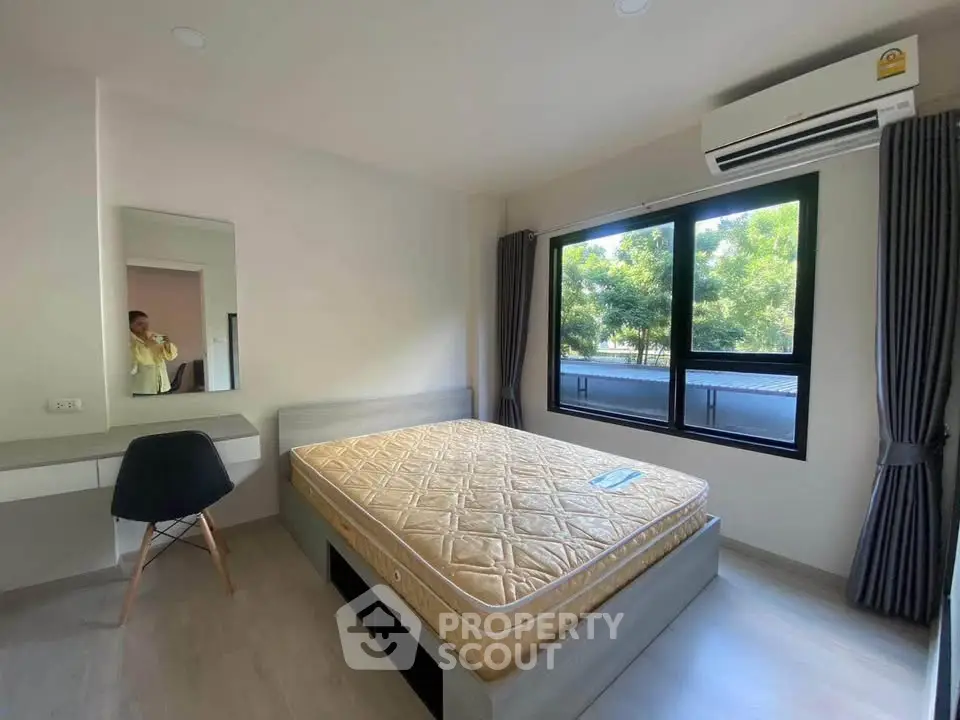 Modern bedroom with large window and air conditioning, featuring a comfortable bed and stylish decor.