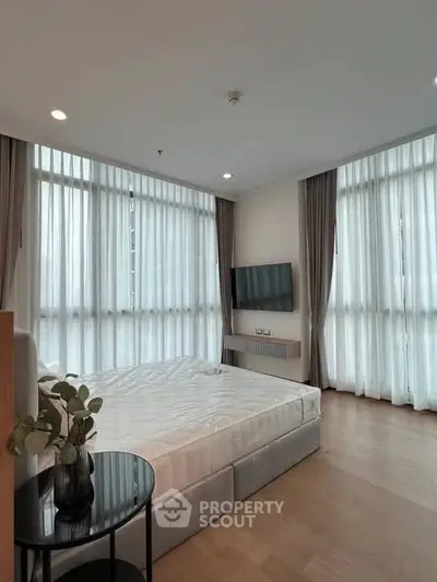 Spacious bedroom with large windows and modern decor in a luxury apartment.