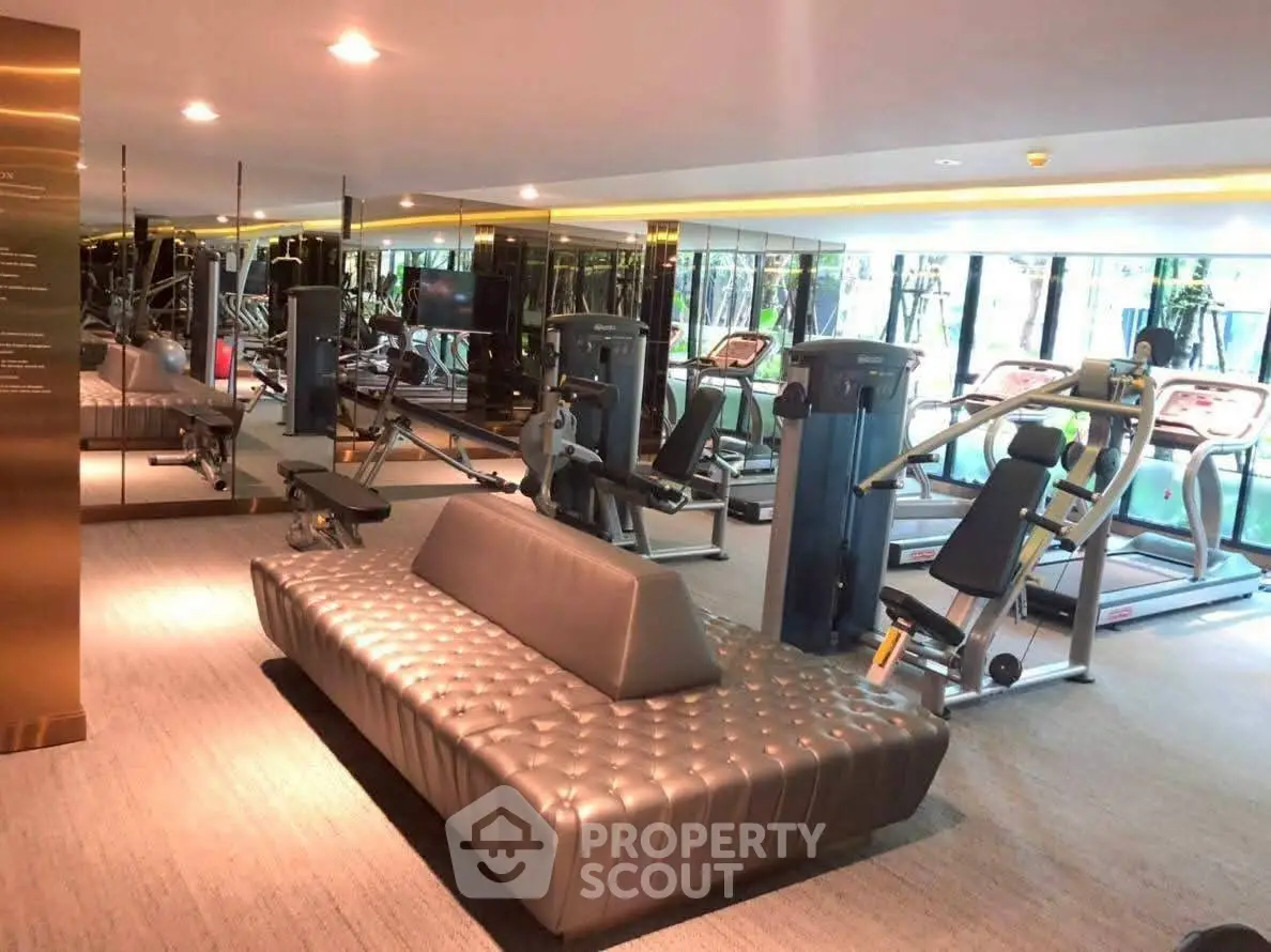 Luxurious gym with modern equipment and stylish seating in upscale residential building.