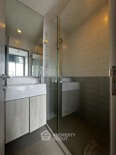 Modern bathroom with glass shower and sleek vanity in contemporary apartment.
