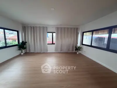 Spacious empty room with large windows and wooden flooring, ideal for customization.