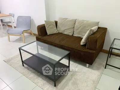 Cozy living room with modern brown sofa and glass coffee table on a plush rug.