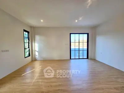 Spacious empty room with large windows and wooden flooring, perfect for customization.