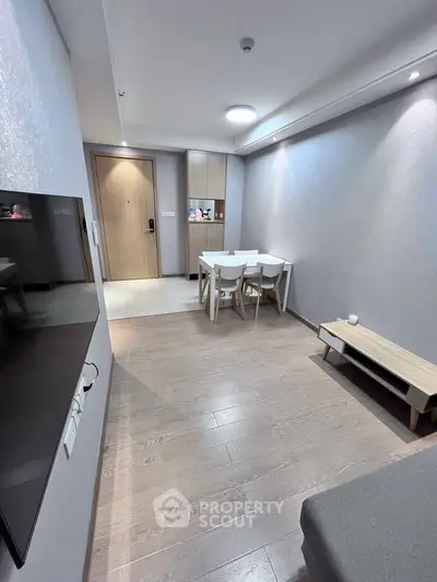 Modern minimalist living room with wooden flooring and dining area in a cozy apartment.