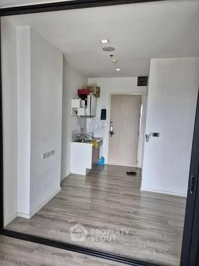 Modern compact apartment with sleek wooden flooring and minimalist kitchen area.