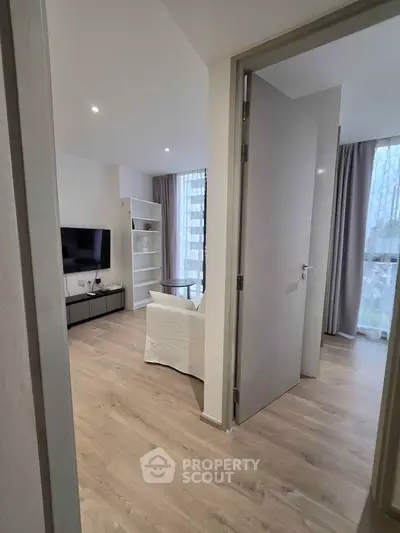 Modern living room with sleek design and natural light, featuring a TV and stylish shelving.