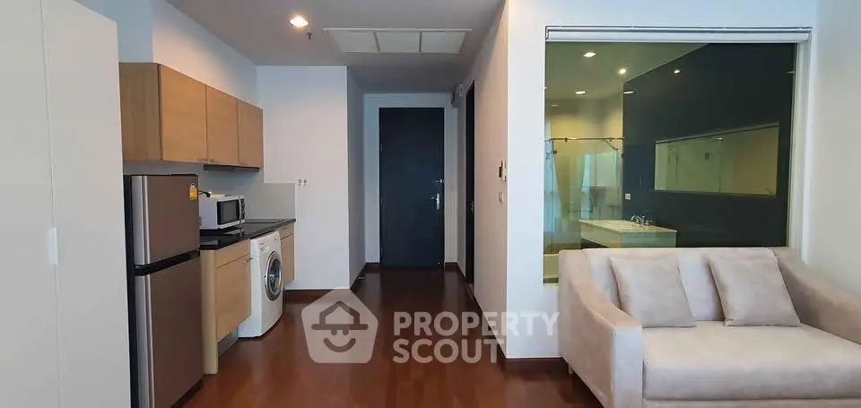 Modern apartment interior with kitchen and living area featuring wooden flooring and sleek design.