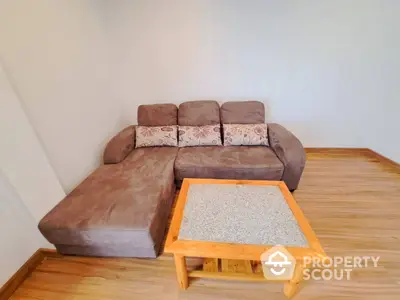 Inviting living space featuring a plush L-shaped sofa with patterned cushions and a wooden coffee table on polished hardwood floors.