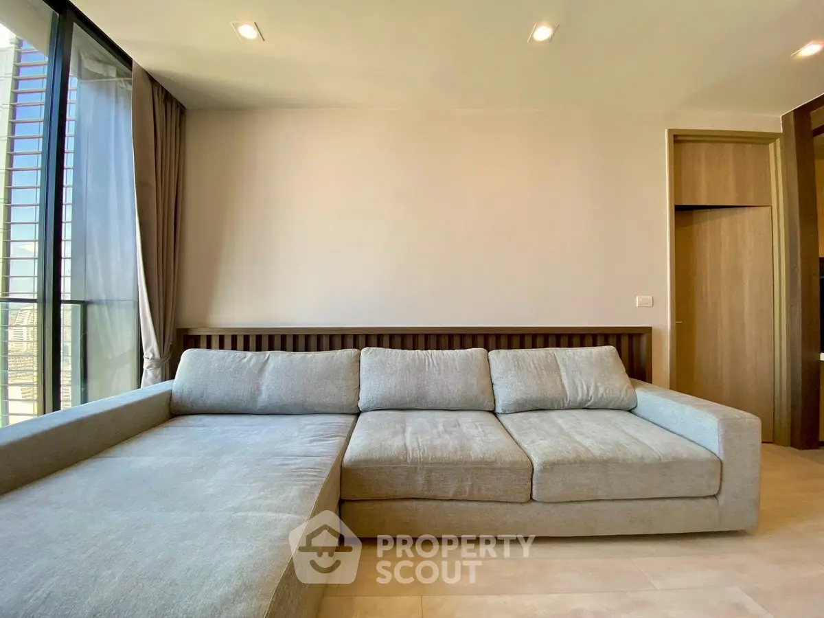 Spacious modern living room with large gray sectional sofa and natural light