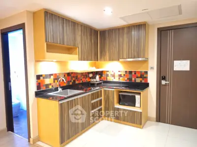 Modern kitchen with vibrant backsplash and sleek cabinetry in a cozy apartment.