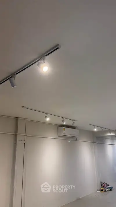 Spacious room with modern track lighting and air conditioning unit, ideal for versatile use.