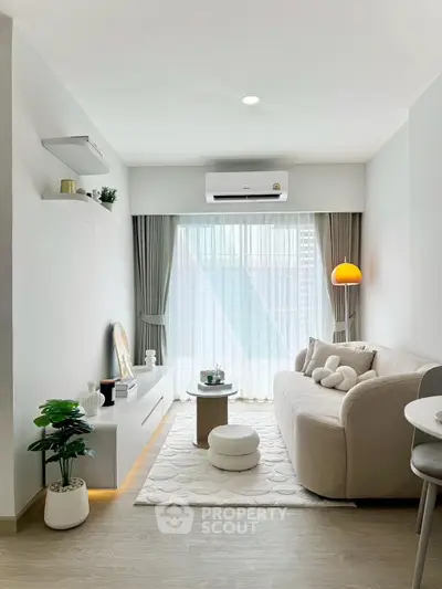 Chic modern living room with cozy sofa, stylish decor, and natural light through large windows.