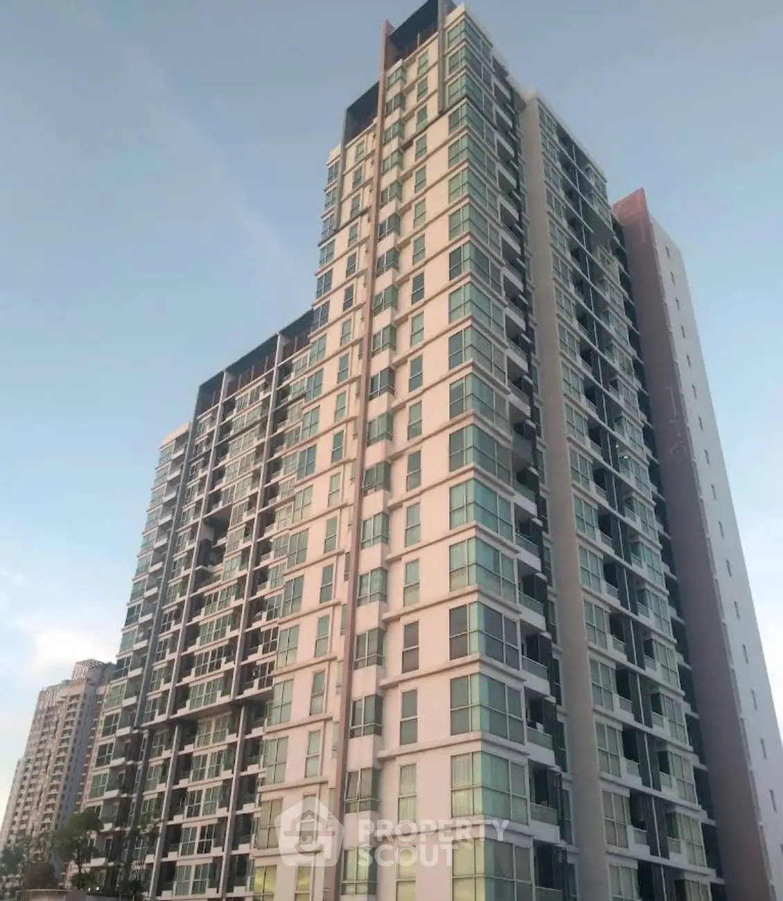 Modern high-rise residential building with sleek glass facade and multiple balconies.