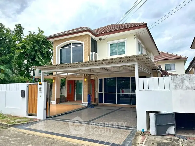 Charming two-story house with tiled driveway and lush greenery, perfect for family living.