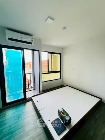 Modern bedroom with air conditioning and balcony access, featuring sleek flooring and minimalist design.