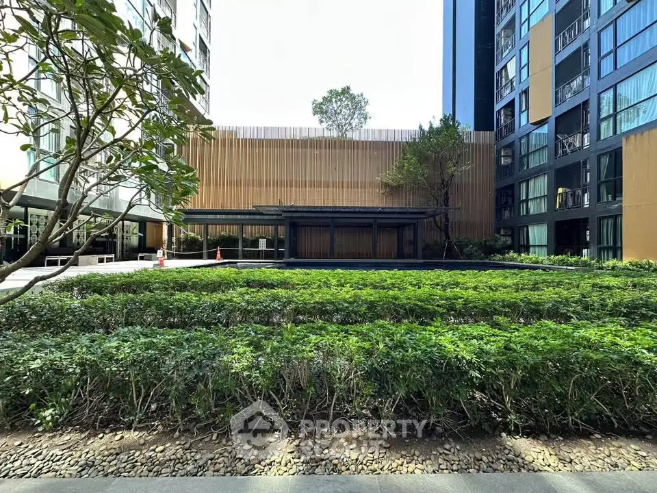 Modern residential building exterior with lush garden and contemporary design.