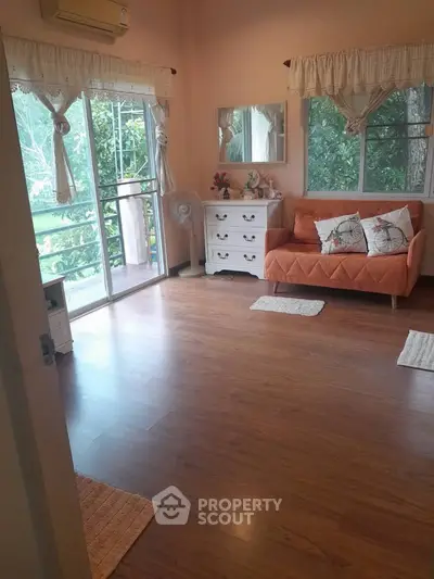 Charming living room with cozy sofa and large windows overlooking lush greenery.