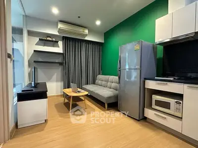 Modern living room with green accent wall, sleek furniture, and kitchen appliances.