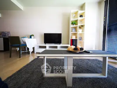 Modern living room with stylish decor and natural light, featuring a cozy rug and sleek furniture.
