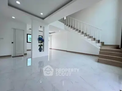 Spacious modern living room with elegant staircase and glossy white flooring