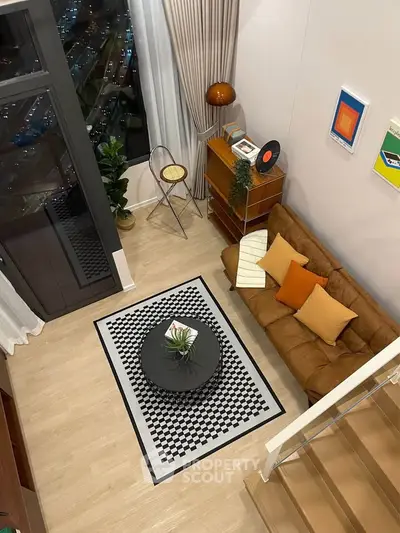 Stylish modern living room with high ceiling, cozy brown sofa, and chic decor in a loft apartment.