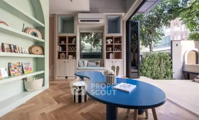 Stylish modern living room with open layout and garden view, featuring unique blue table and built-in shelves.