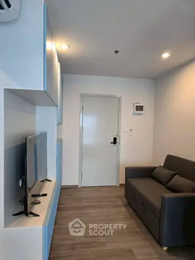 Modern living room with sleek furniture and wall-mounted TV in a cozy apartment.