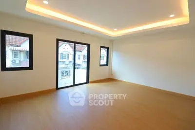 Spacious empty room with wooden flooring and large windows offering natural light