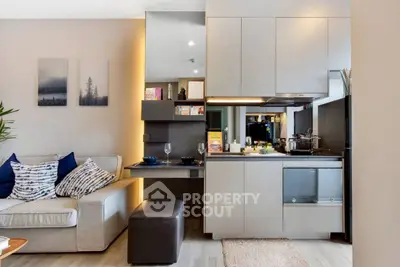 Modern living room with open kitchen, sleek cabinetry, and cozy seating area in stylish apartment.