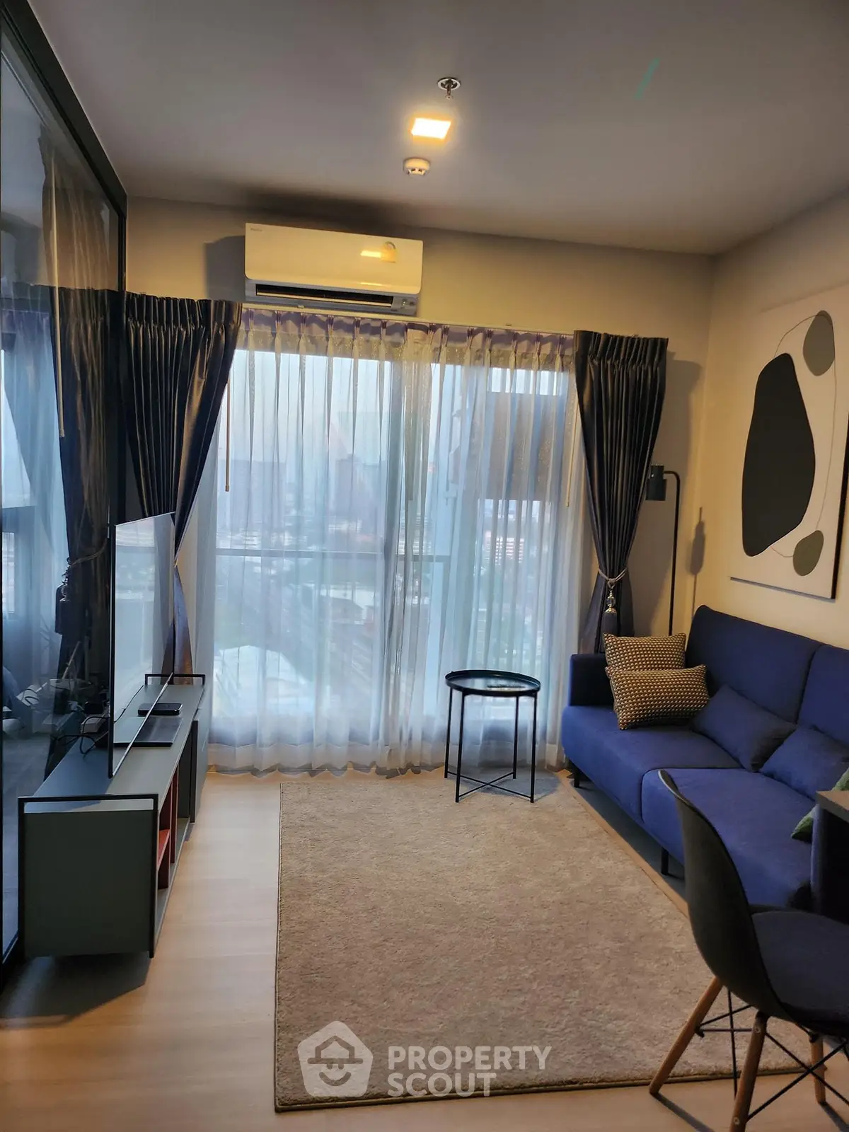 Modern living room with blue sofa, large window, and stylish decor in a cozy apartment.