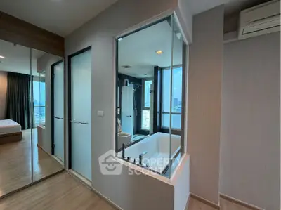 Modern apartment interior with glass-walled bathroom and city view, featuring sleek design and wooden flooring.