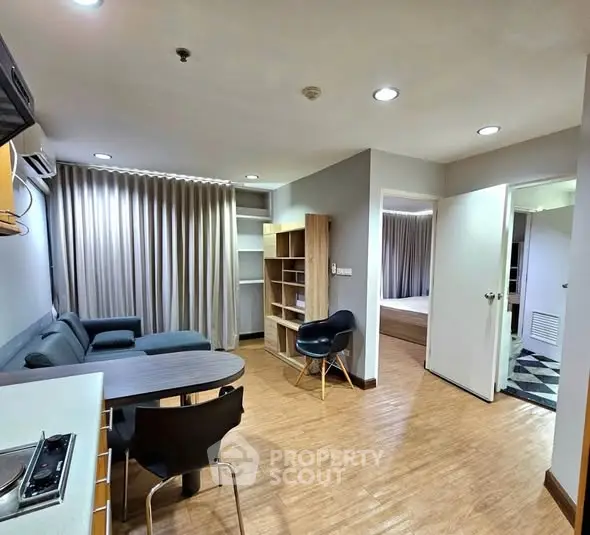 Modern apartment interior with open living room and kitchen, featuring stylish furniture and wooden flooring.