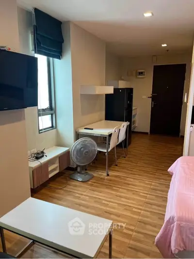Cozy studio apartment with modern furnishings and wooden flooring, featuring a compact kitchen and dining area.