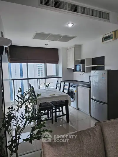 Modern kitchen with dining area, featuring large windows and sleek appliances in a stylish apartment.