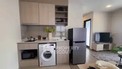 Modern kitchen with integrated appliances and cozy living area in open layout apartment.