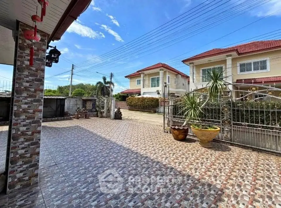 Spacious tiled courtyard with charming suburban houses and clear blue sky.