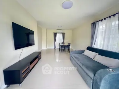 Spacious living room with modern decor and large TV, perfect for relaxation and entertainment.