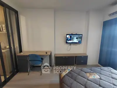 Modern bedroom with TV, desk, and comfortable bed in stylish apartment.