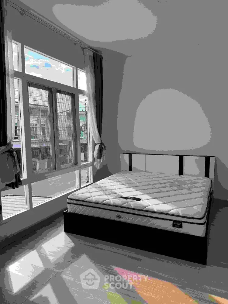 Bright bedroom with large windows and a comfortable mattress, perfect for relaxation.