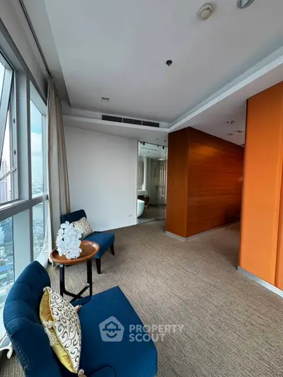 Spacious modern living area with city view, elegant decor, and cozy seating in a high-rise apartment.