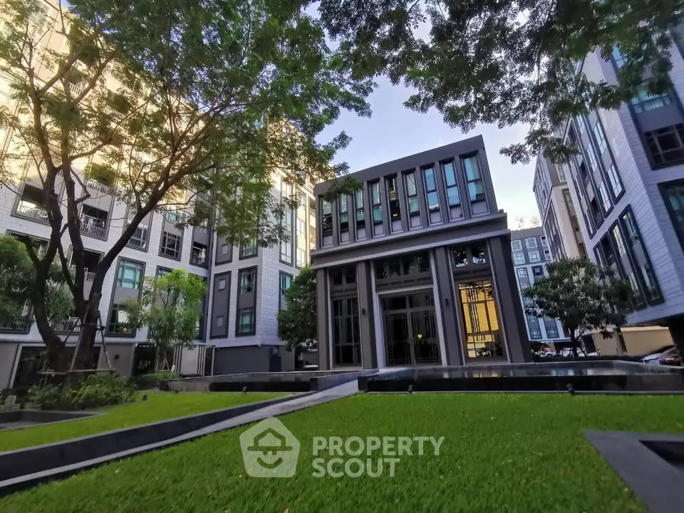 Modern apartment complex with lush green lawn and contemporary architecture.
